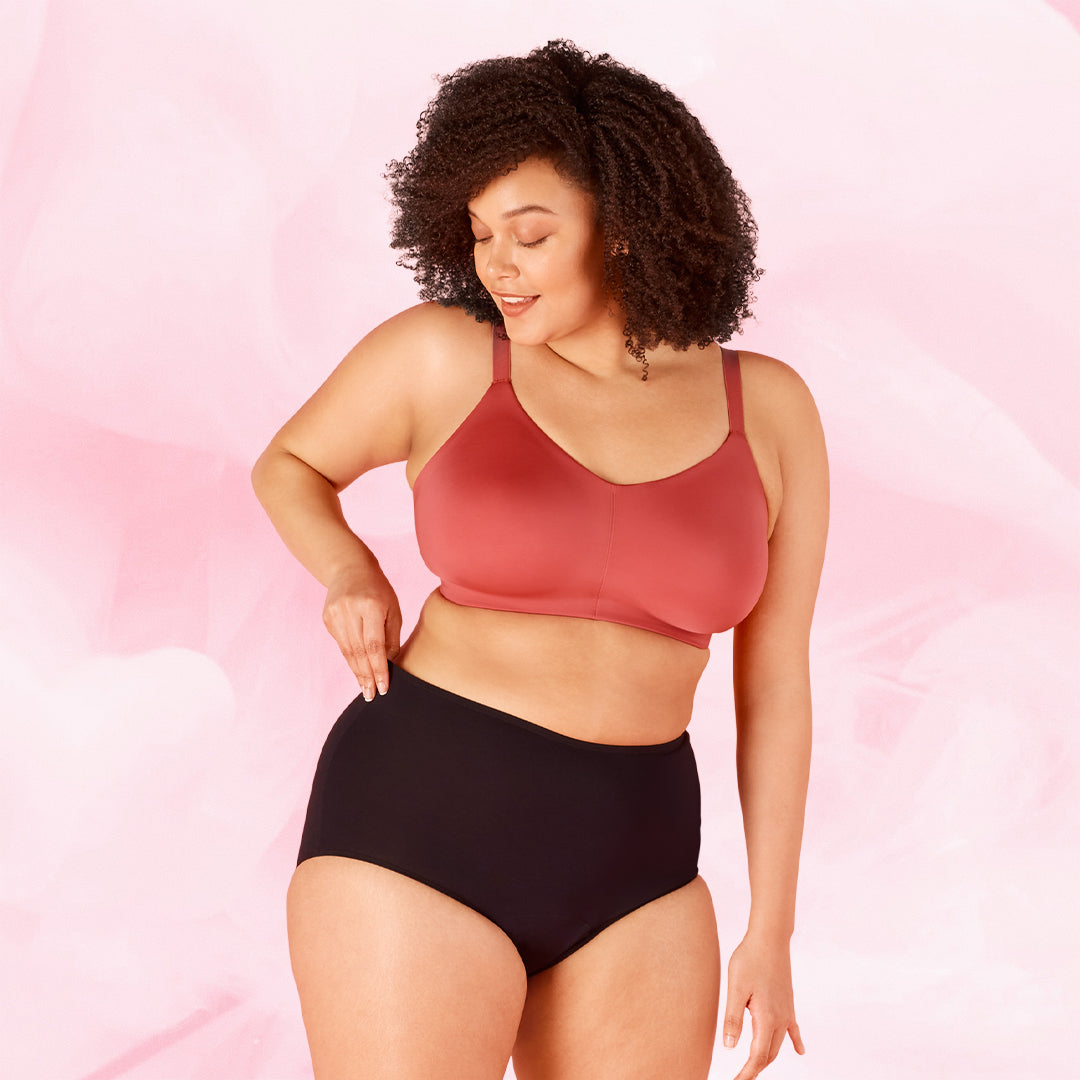 Plus-kokoinen nainen esittelee ComfortFit Sleepwear High Waist -kuukautisalushousuja.