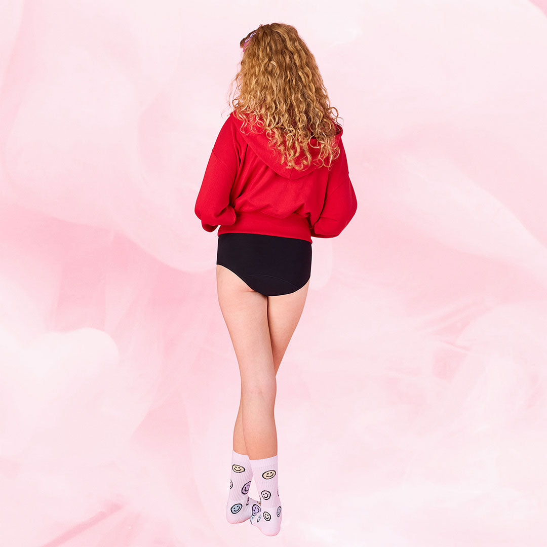 Henkilö pukeutuneena punaisiin huppariin, esittelee Teens Hipster Kohtalainen vuoto 5-pack.